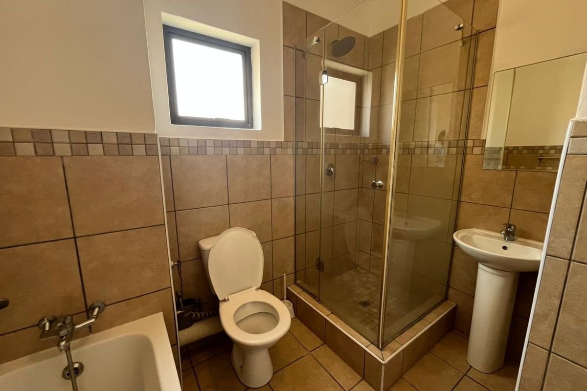 A functional bathroom featuring a separate shower enclosure, pedestal basin, toilet, and bathtub with neutral tiled finishes throughout.