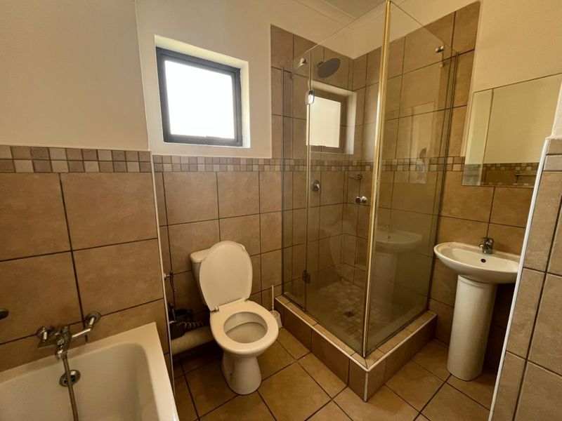 A functional bathroom featuring a separate shower enclosure, pedestal basin, toilet, and bathtub with neutral tiled finishes throughout.