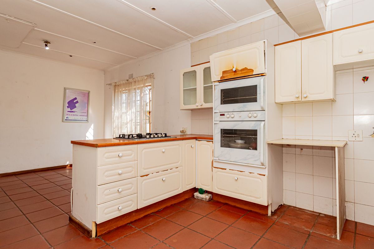 A dated kitchen featuring built-in cabinetry, a gas hob, and a double oven, requiring cosmetic updates and repairs to the cabinetry and finishes.
