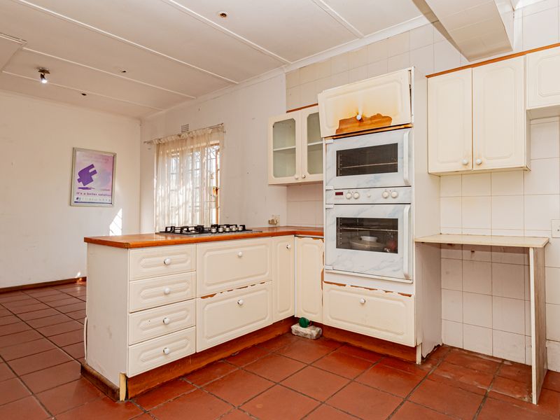A dated kitchen featuring built-in cabinetry, a gas hob, and a double oven, requiring cosmetic updates and repairs to the cabinetry and finishes.