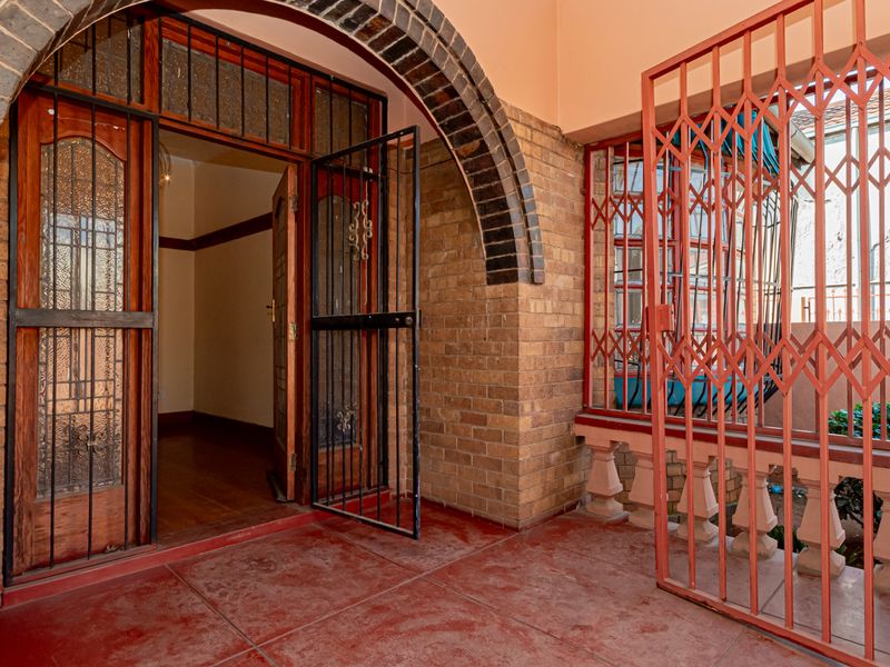 Covered patio area featuring a brick archway, security gate, and balustrade, providing a secure entrance to the home.