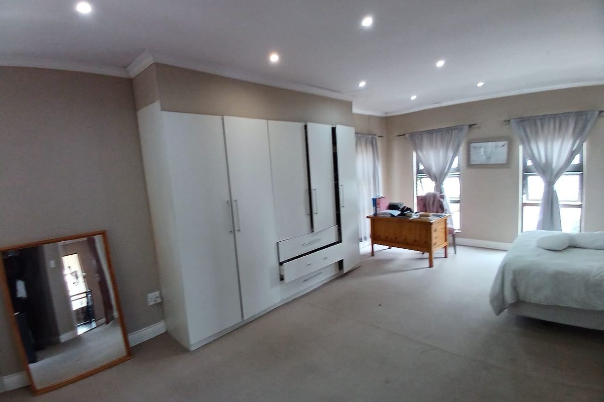 Spacious bedroom featuring built-in cupboards, recessed downlighting, and large windows allowing for ample natural light.