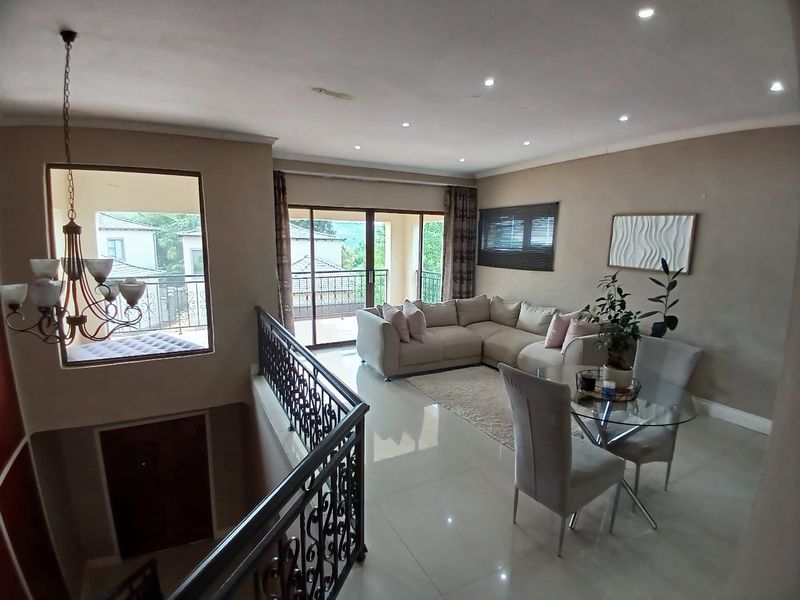 Spacious open-plan living and dining area featuring tiled flooring, recessed lighting, and a decorative wrought iron balustrade overlooking the lower level.