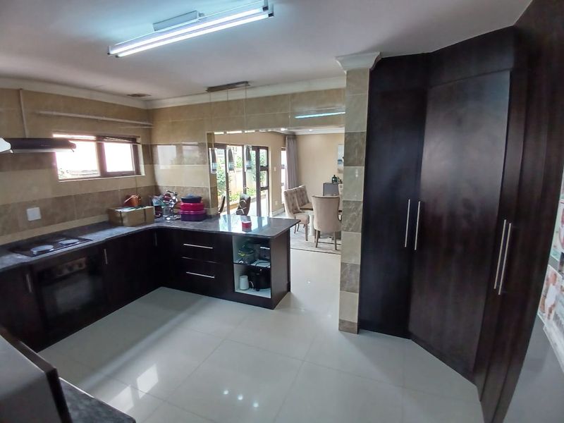 Open-plan kitchen featuring dark wood cabinetry, granite countertops, and integrated appliances, flowing seamlessly into the adjacent dining area.