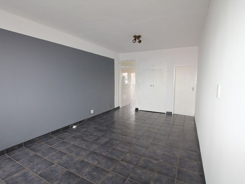 An empty bedroom featuring dark tiled flooring, a grey accent wall, and built-in storage cupboards.