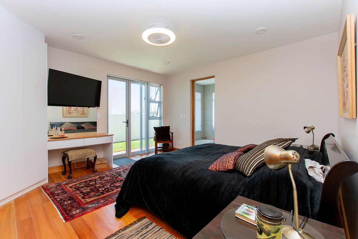 Spacious bedroom featuring hardwood flooring, built-in wardrobe, ceiling fan, and direct access to an outdoor area and en-suite bathroom.