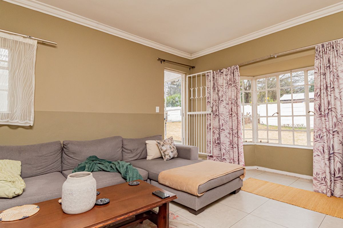A living room featuring tiled flooring, a bay window, and a security gate providing access to the exterior.
