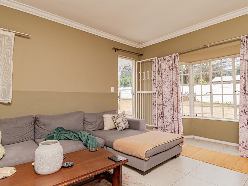 A living room featuring tiled flooring, a bay window, and a security gate providing access to the exterior.