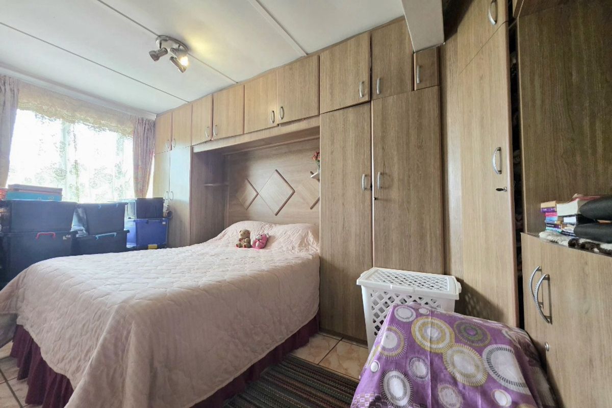 A bedroom featuring extensive built-in wooden cabinetry and tiled flooring, offering ample storage space.