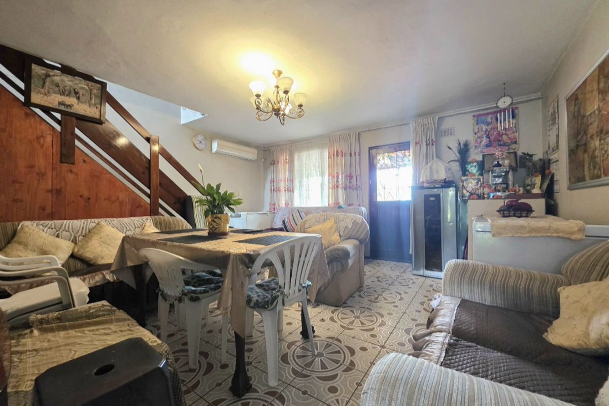 A living room featuring tiled flooring, a staircase, and a wall-mounted air conditioning unit, offering a functional space for relaxation.