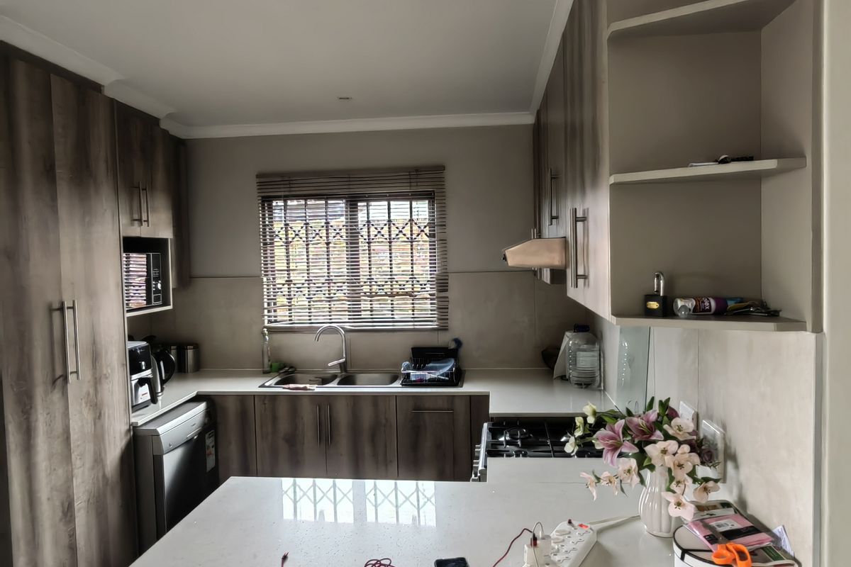 Modern kitchen featuring wood-grain cabinetry, stone countertops, integrated appliances, and a breakfast bar, providing a functional and contemporary cooking space.