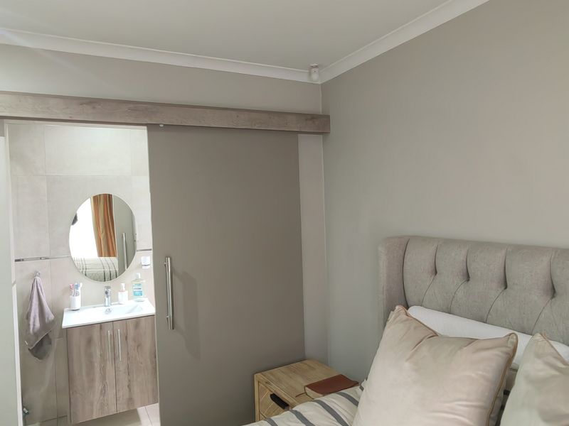 A well-maintained bedroom featuring a modern sliding barn door that opens into an en-suite bathroom with a vanity and mirror.