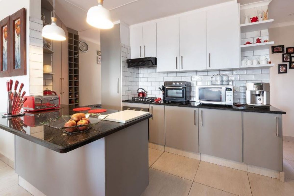 Modern kitchen featuring granite countertops, subway tile backsplash, ample cabinetry, and a built-in wine rack, creating a functional and stylish culinary space.
