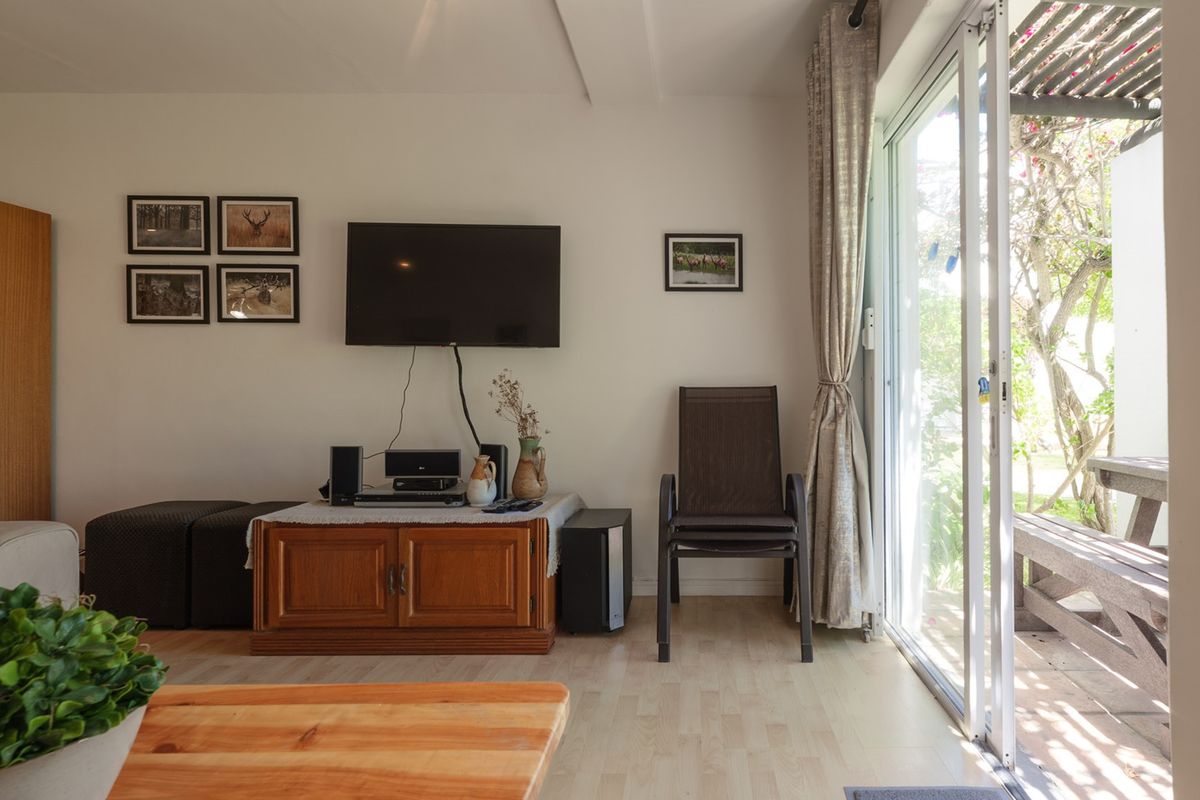 A living room featuring laminate flooring and a large sliding glass door providing direct access to an outdoor patio area.