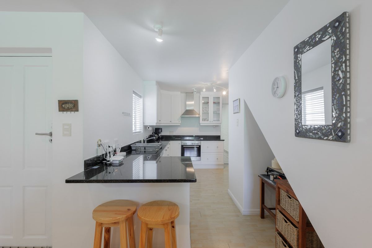 A well-maintained kitchen featuring granite countertops, built-in oven, extractor fan, and ample cabinetry, with a breakfast bar overlooking the space.