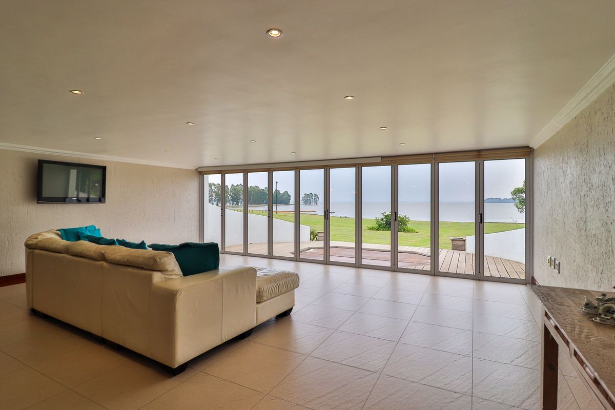 Spacious living area featuring large aluminium stacker doors that open onto a patio with scenic water views and modern recessed lighting.