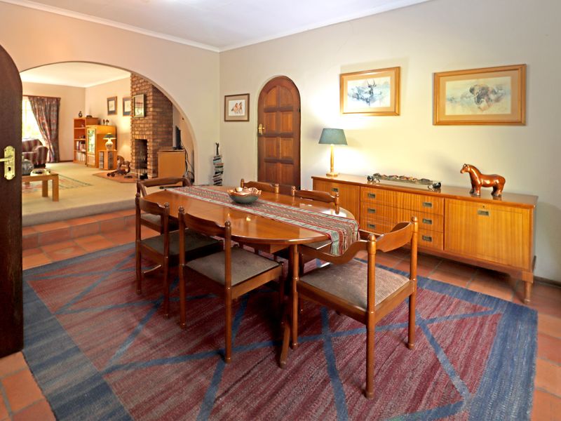 Dining room featuring terracotta floor tiles, an arched doorway leading to a sunken living area, and a classic brick fireplace.