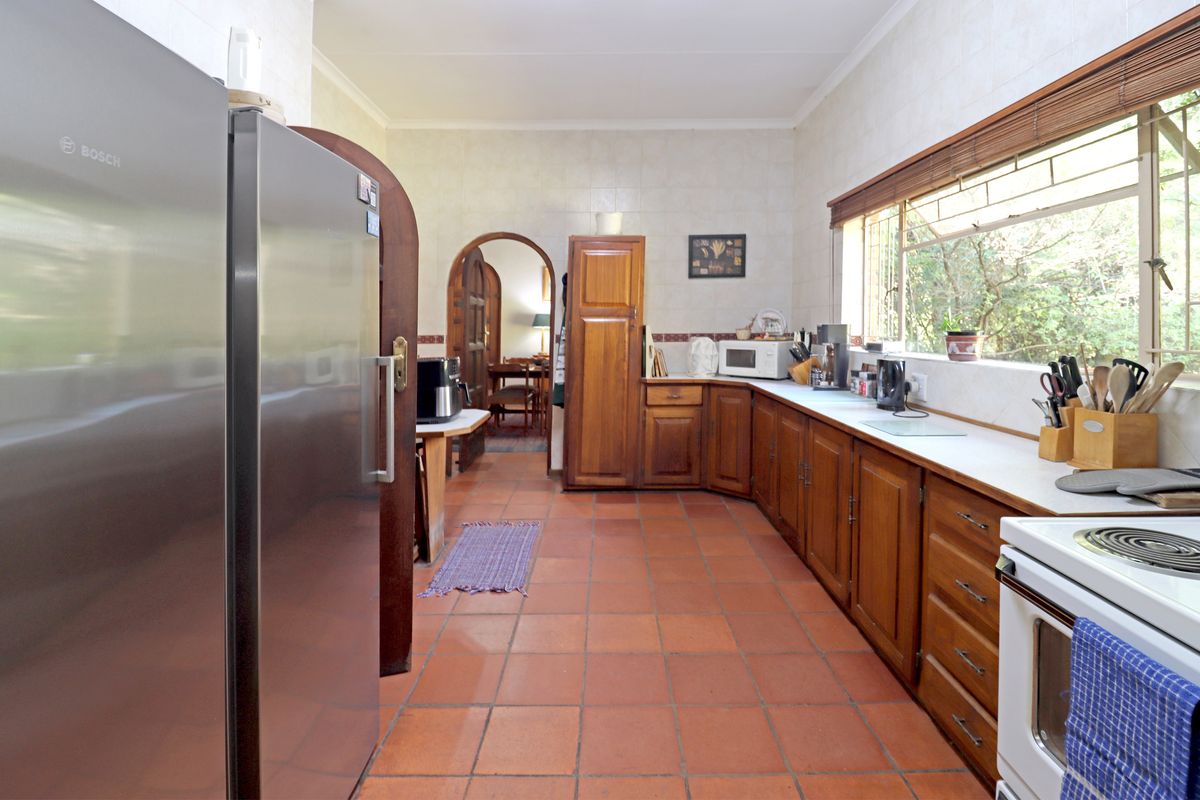 A functional kitchen featuring traditional wooden cabinetry, terracotta floor tiles, and a tiled splashback, offering a classic layout with ample storage space.