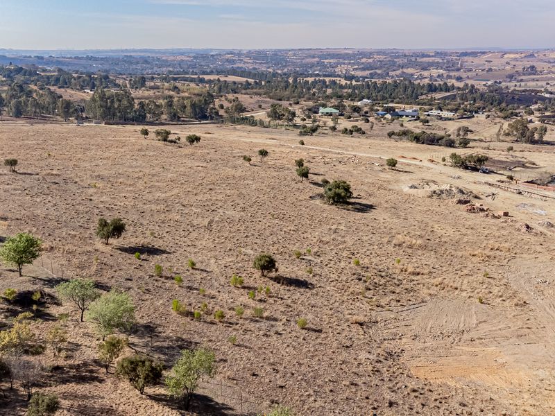 An aerial view of a large, undeveloped residential plot featuring native vegetation and surrounding landscape views.