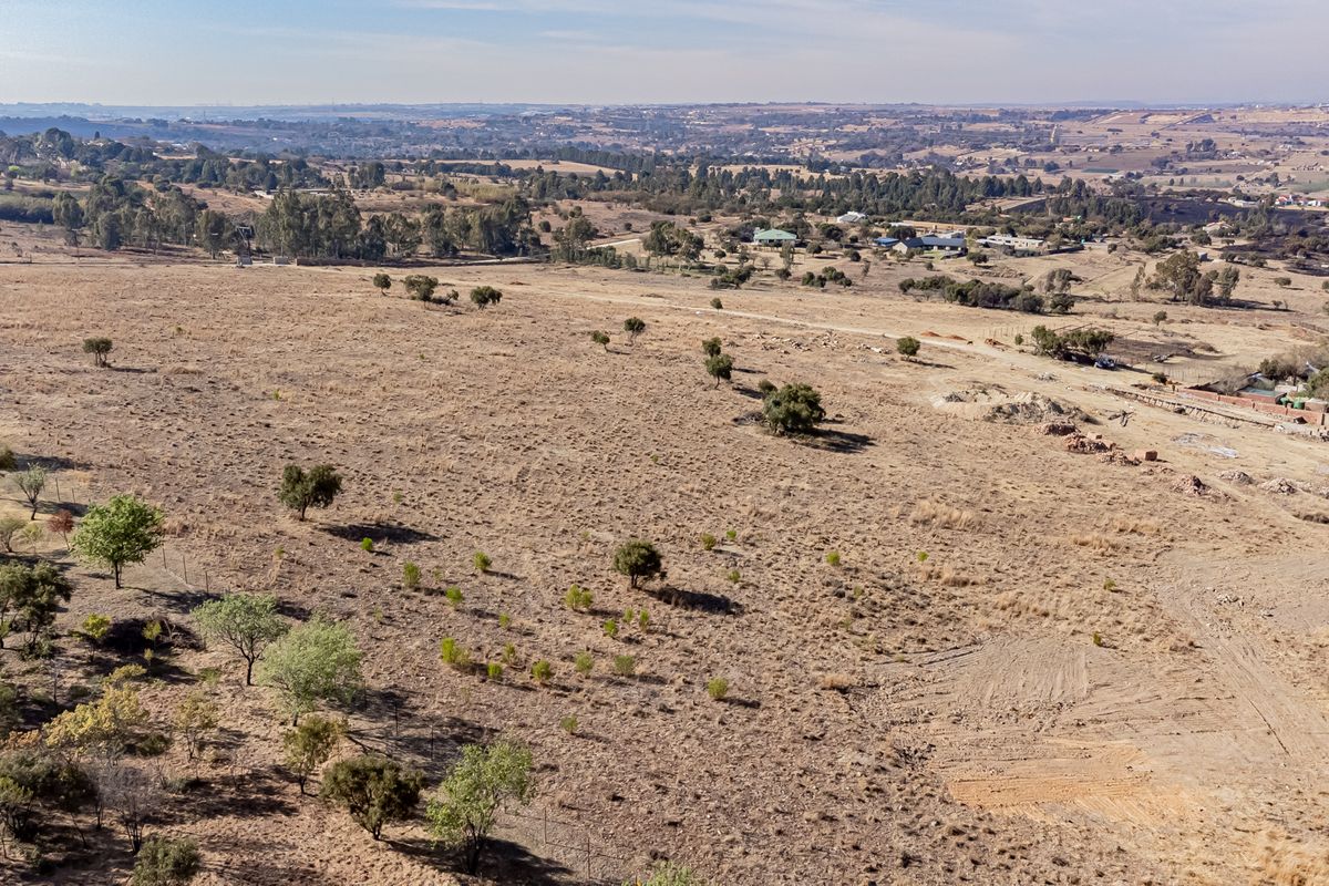 An aerial view of a large, undeveloped residential plot featuring native vegetation and surrounding landscape views.