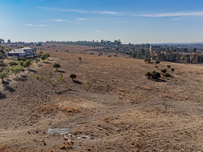 An aerial view of a large, open residential vacant land plot featuring natural vegetation and perimeter fencing.