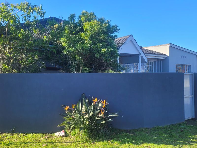 Front view of the property featuring a solid boundary wall, pedestrian gate, and tiled roof structure.