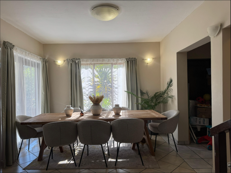 A bright dining room featuring tiled flooring, wall sconces, and sliding glass doors that provide natural light and access to the exterior.