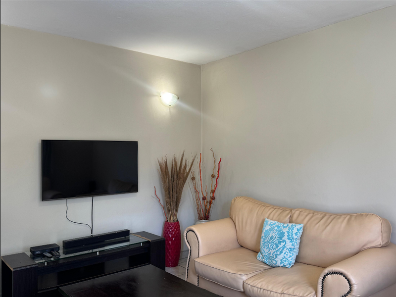 A living room area featuring neutral wall tones and a wall-mounted light fixture.