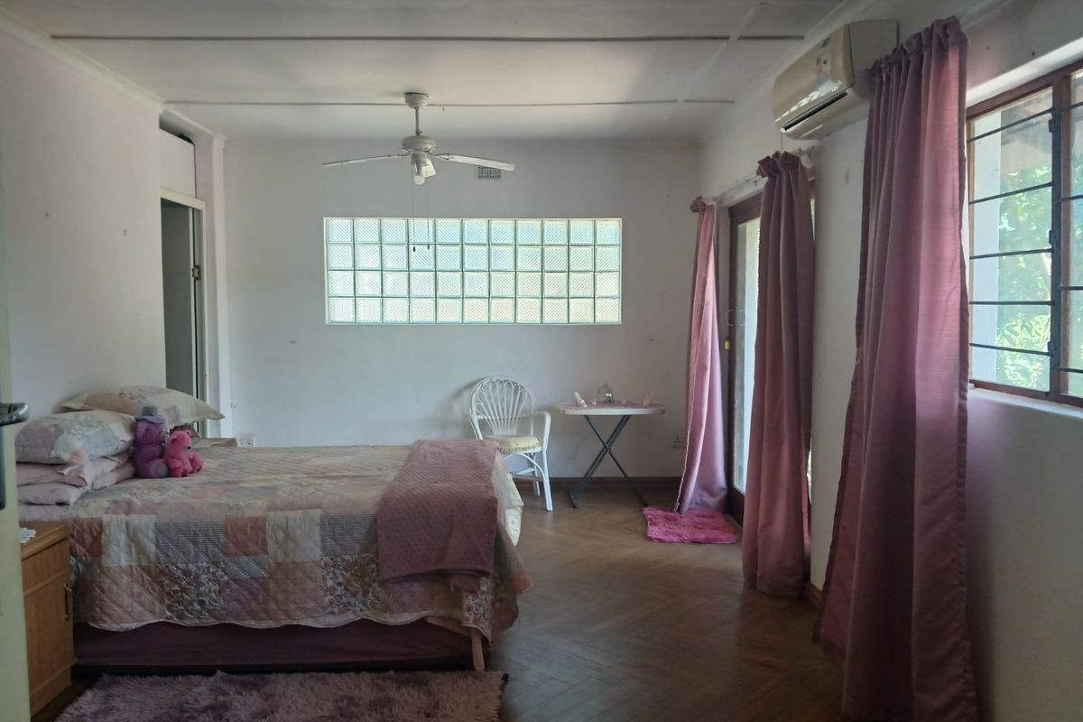 Spacious bedroom featuring parquet flooring, a ceiling fan, split-system air conditioning, and a unique glass block window providing natural light.