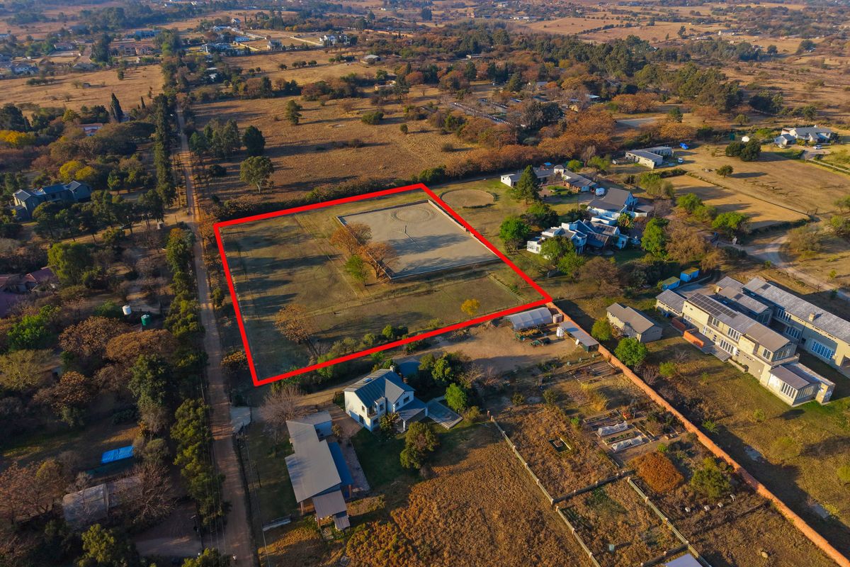 Aerial view of a vacant residential plot with a clearly marked boundary, situated in a semi-rural neighborhood setting.