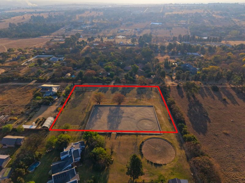 Aerial view of a vacant residential plot featuring an established equestrian arena and round pen, set within a semi-rural landscape.