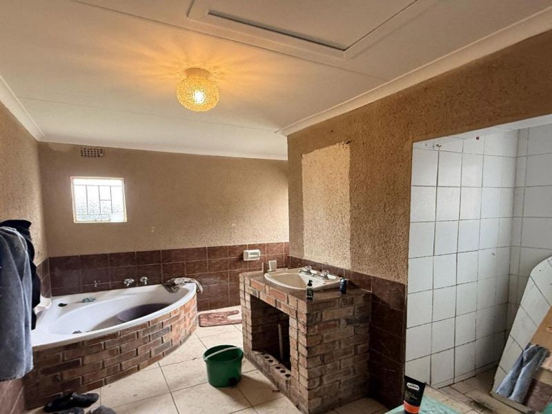 A dated bathroom featuring a corner bathtub, brick-based vanity, and a separate tiled shower area, requiring renovation to modernize the finishes and fixtures.