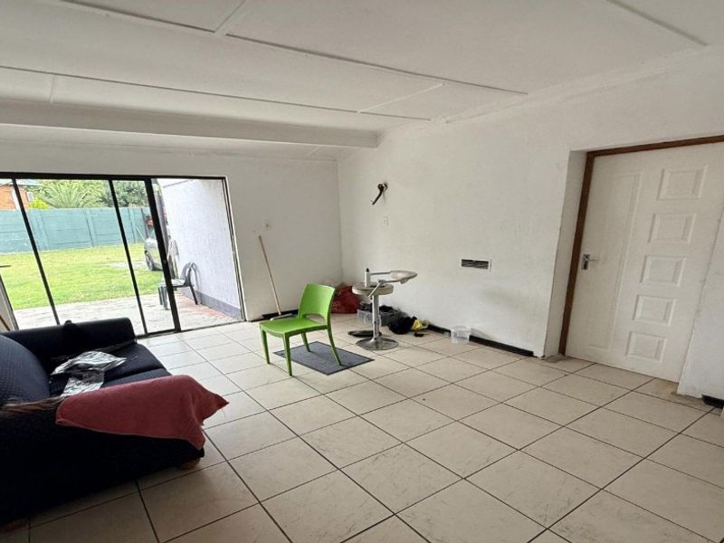 A living area featuring tiled flooring and a sliding glass door providing direct access to the rear garden.