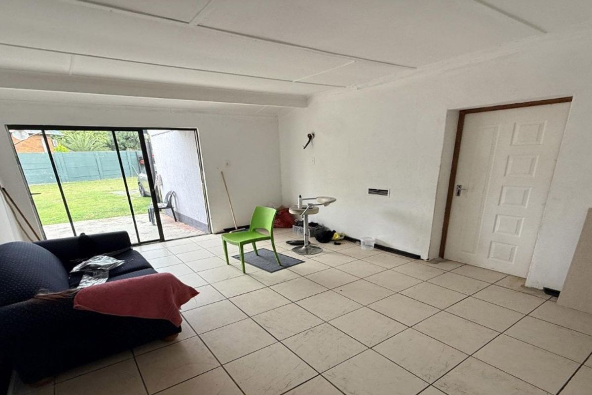 A living area featuring tiled flooring and a sliding glass door providing direct access to the rear garden.