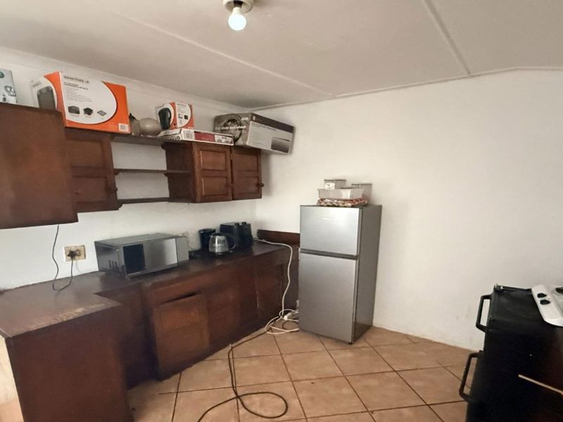 A functional kitchen space featuring wooden cabinetry, tiled flooring, and ample counter space, offering potential for modernization and aesthetic updates.