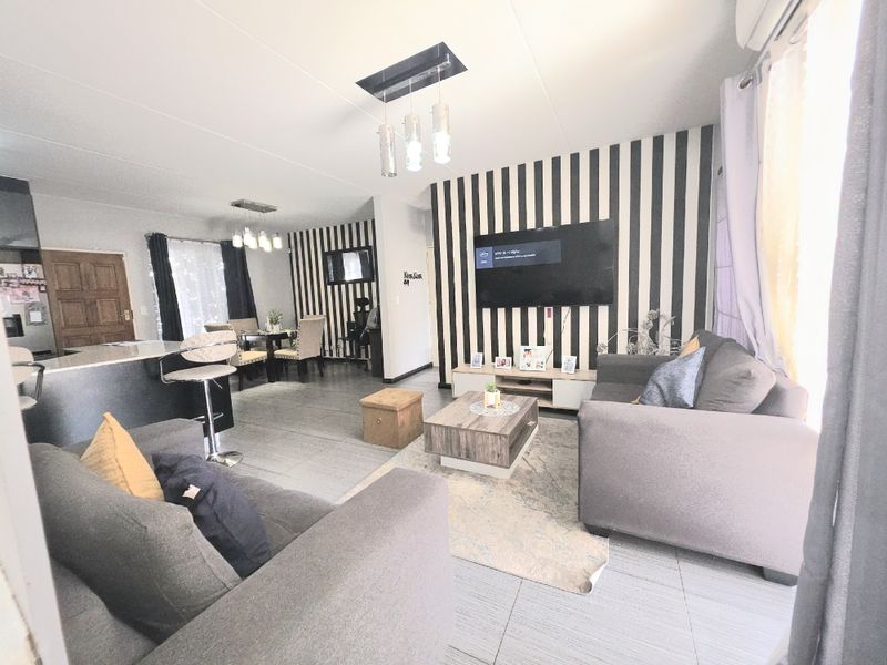 An open-plan living and dining area featuring tiled flooring, modern pendant lighting, and a kitchen island, creating a cohesive and functional living space.