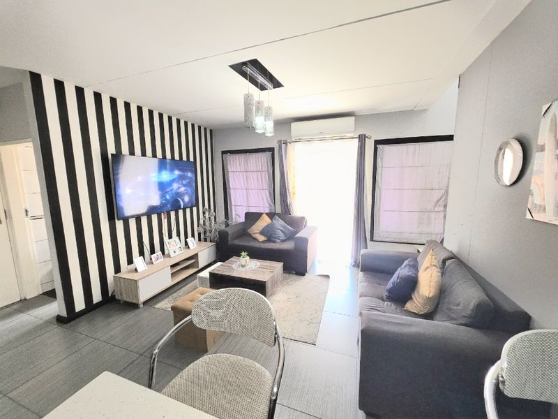 A living room featuring tiled flooring, a split-system air conditioner, and recessed ceiling lighting, providing a functional and comfortable space.