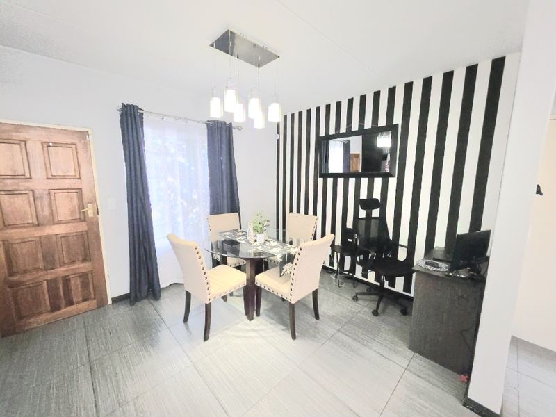 Dining area featuring tiled flooring, a modern pendant light fixture, and a feature wall with striped wallpaper.