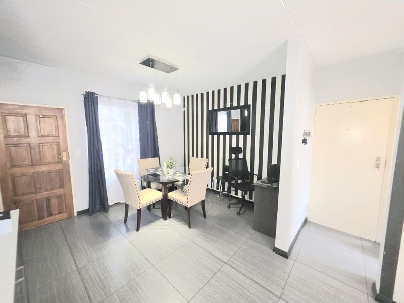 Dining area featuring tiled flooring, a modern pendant light fixture, and a solid wood door, providing a functional space for meals.