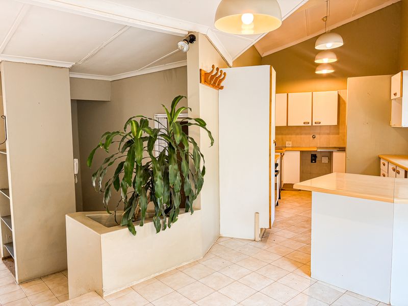Open plan kitchen area featuring tiled flooring, built-in cabinetry, and a unique integrated planter box, offering a functional layout with potential for modernization.