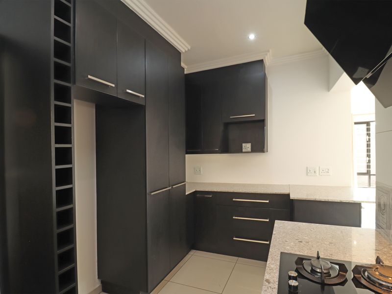 Modern kitchen featuring dark cabinetry, stone countertops, a built-in gas hob with extractor fan, and integrated wine storage.