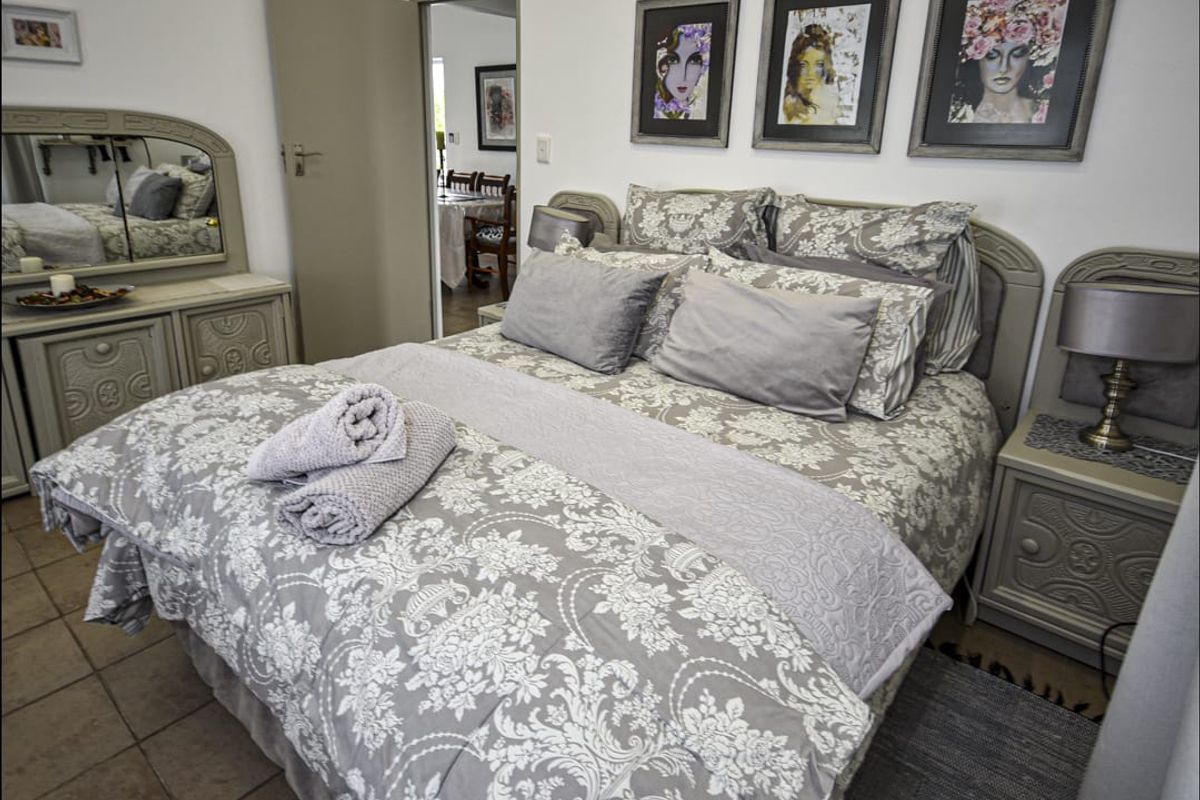 A well-maintained bedroom featuring tiled flooring and a neutral color palette, with a doorway leading to an adjacent living area.