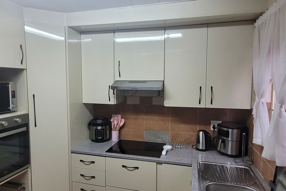 A functional kitchen featuring built-in cabinetry, an integrated oven and microwave, an induction hob with extractor fan, and a stainless steel sink.