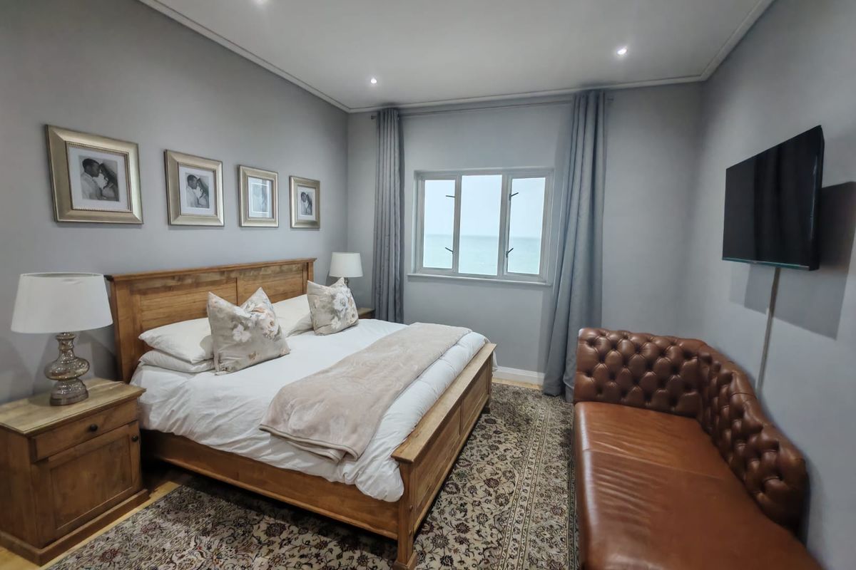 A well-maintained bedroom featuring neutral grey walls, recessed lighting, and a window with a view, creating a comfortable and inviting living space.