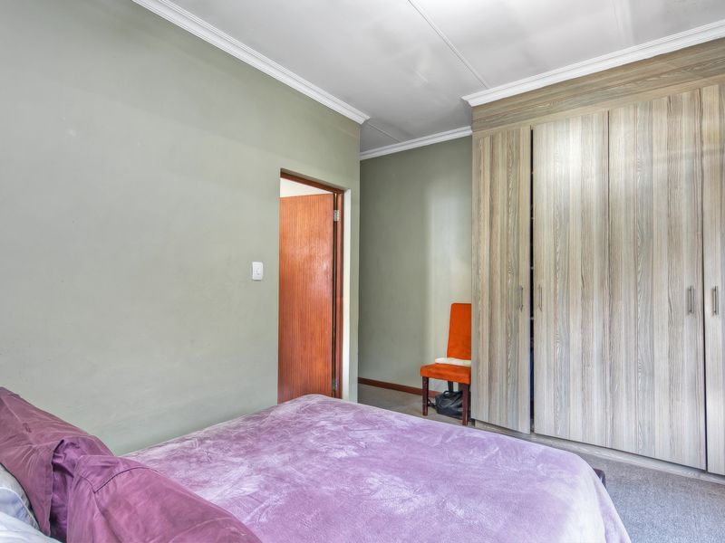 A bedroom featuring built-in wooden cupboards, crown molding, and carpeted flooring, providing a functional and neutral living space.