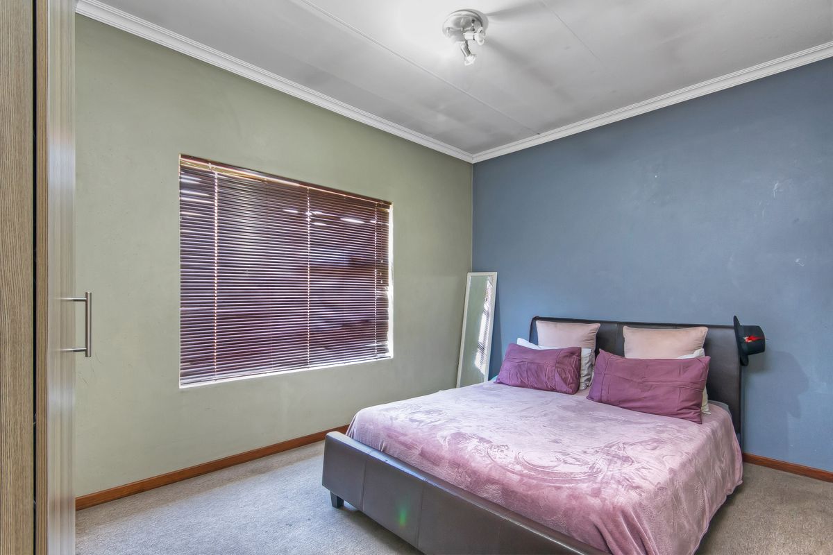 A bedroom featuring carpeted flooring, built-in wardrobe storage, and venetian blinds, offering a functional space with potential for cosmetic updates.