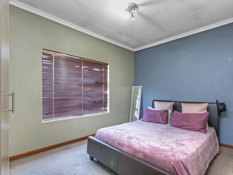 A bedroom featuring carpeted flooring, built-in wardrobe storage, and venetian blinds, offering a functional space with potential for cosmetic updates.