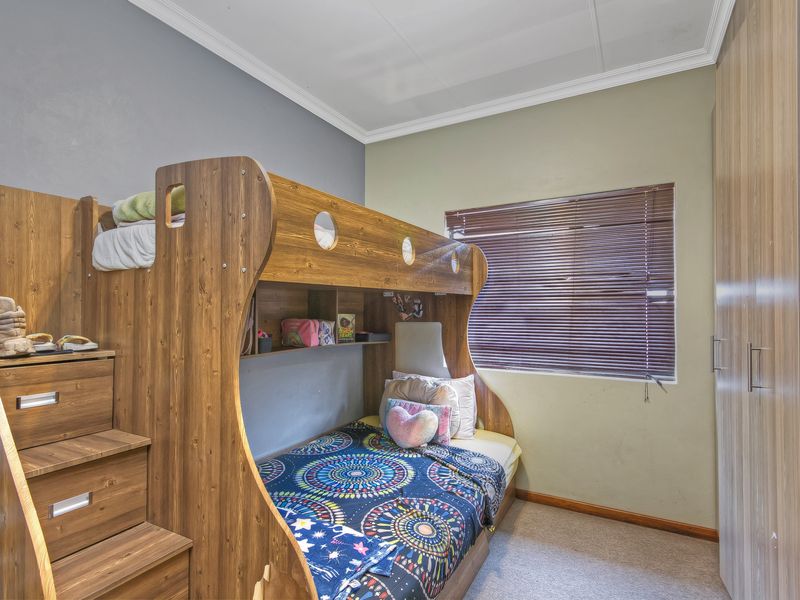 A functional bedroom featuring carpeted flooring, a built-in wardrobe, and venetian blinds, providing a practical space for rest or study.