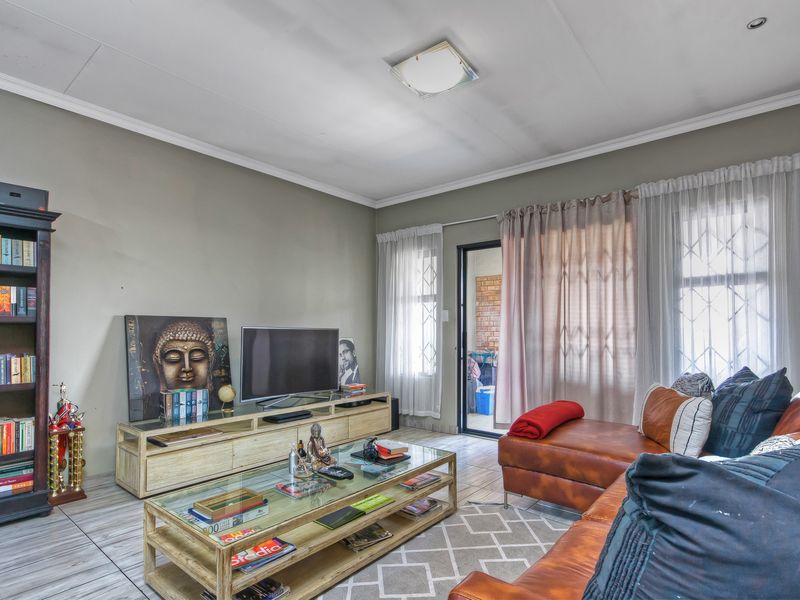 A comfortable living room featuring tiled flooring, neutral wall tones, and direct access to an outdoor patio area through a sliding door.
