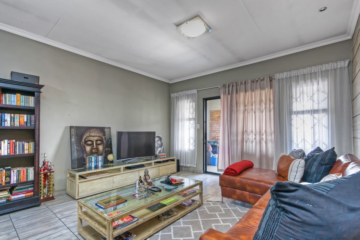A comfortable living room featuring tiled flooring, neutral wall tones, and direct access to an outdoor patio area through a sliding door.